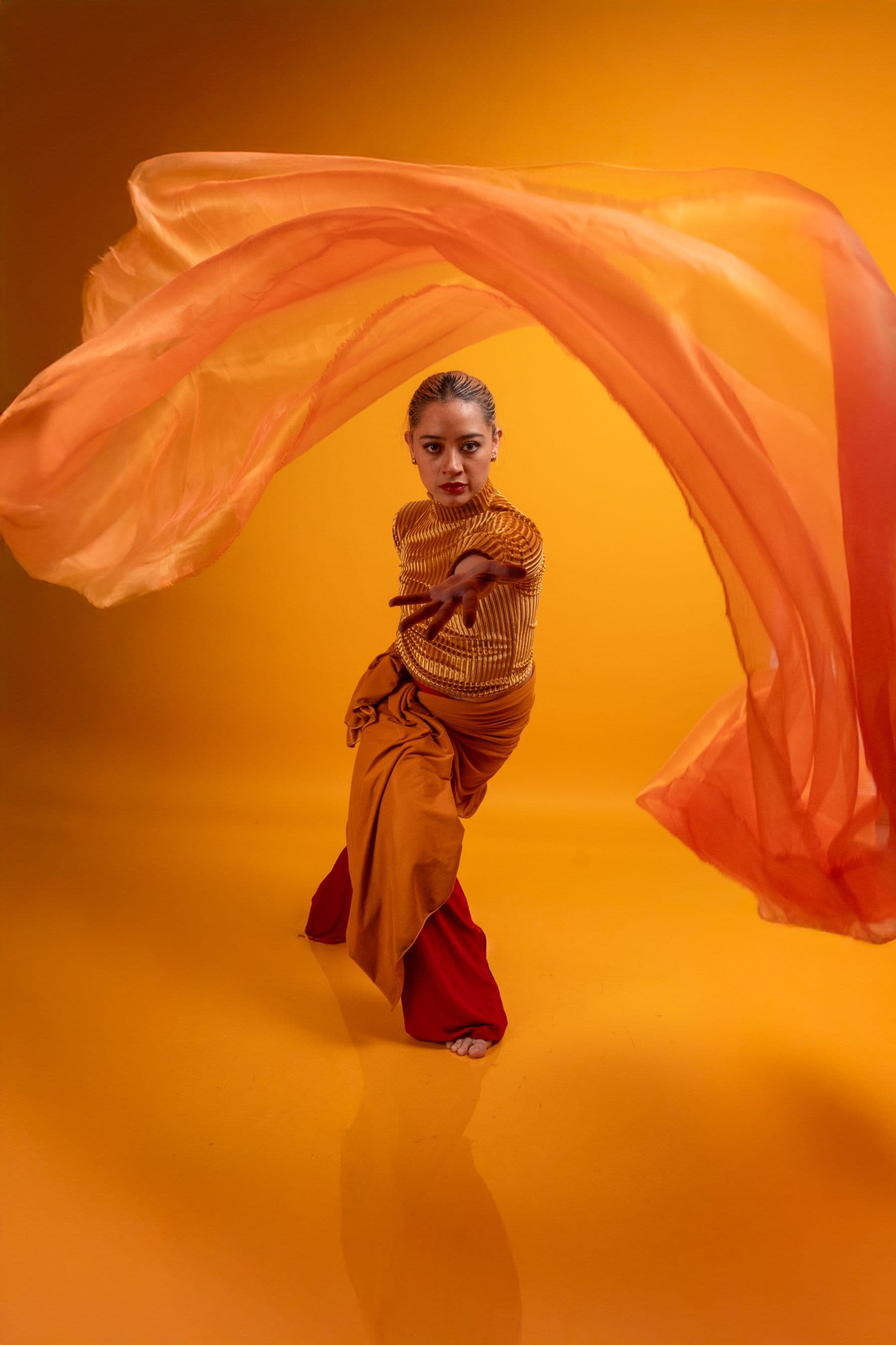 A contemporary dancer moving through orange fabric